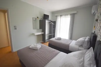 a hotel room with two beds and a window at K&C Rooms- Apartments in Markopoulo