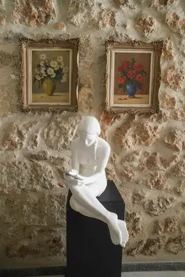 a statue of a woman sitting on a box in front of two paintings at Little gem in the historical center of Athens in Athens