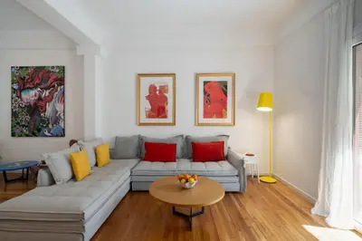 a living room with a couch with red and yellow pillows at Ebullience - Stylish & Chic Athens Apartment in Athens