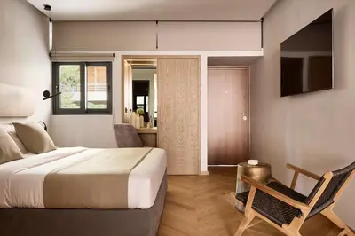 a bedroom with a bed and a chair and a television at Cama Luxury Suites Kavouri in Athens