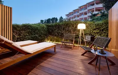 a patio with a bed and chairs on a wooden deck at Cama Luxury Suites Kavouri in Athens