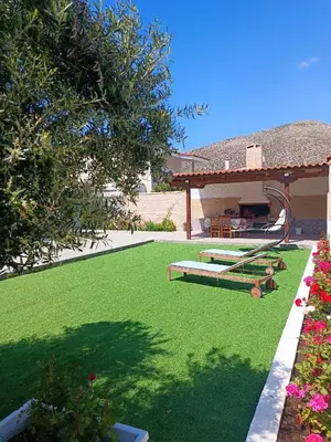 a yard with green grass and a house with a playground at New Olivka House in Anavissos