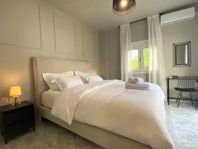 a bedroom with a bed with white sheets and a window at Sand by Aestas Suites in Artemida