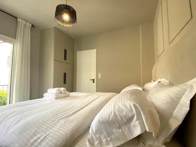 a bedroom with a white bed with white pillows at Sand by Aestas Suites in Artemida