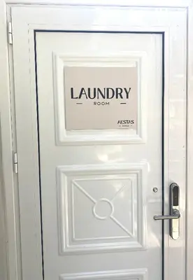 a white door with a laundry room sign on it at Sand by Aestas Suites in Artemida
